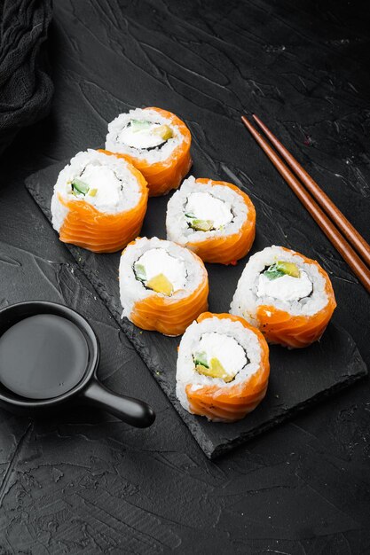 Conjunto de rolos de sushi japonês fresco tradicional, em fundo de pedra preta