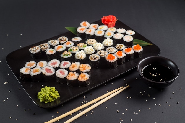 Conjunto de rolos de sushi japonês servido em chapa preta em fundo escuro