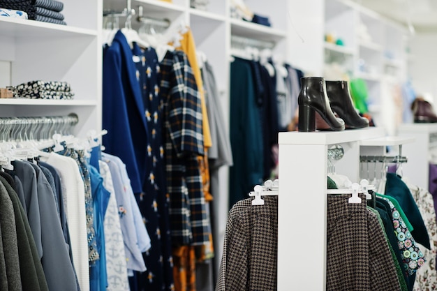 Conjunto de roupas coloridas femininas nas prateleiras com sapatos na loja de roupas nova boutique moderna