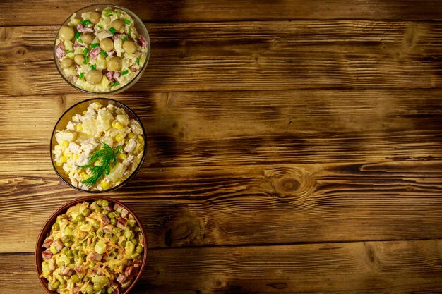 Conjunto de saladas de maionese festivas na mesa de madeira. Vista superior, copie o espaço