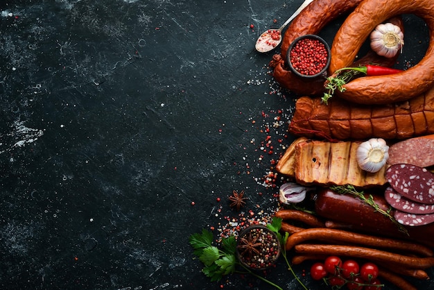 Conjunto de salame de salsicha e carne defumada com alecrim e especiarias em um fundo de pedra preta Vista superior Espaço livre para texto