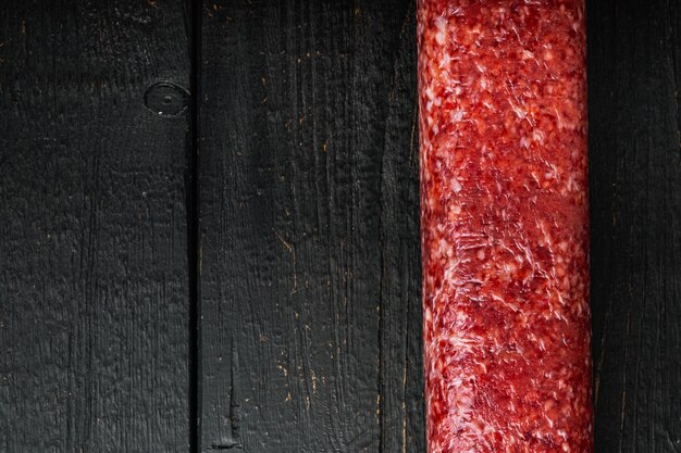 Conjunto de salame fresco, mesa de madeira preta, vista de cima plana