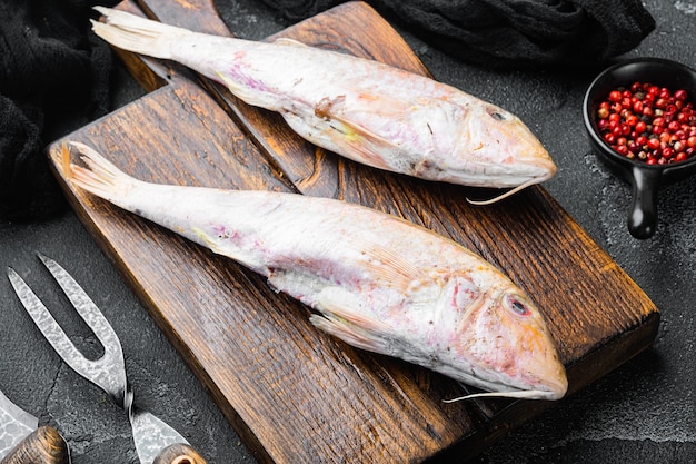 Conjunto de salmonete cru fresco ou peixe inteiro barabulka, com ingredientes e ervas, no fundo da mesa de pedra escura e preta