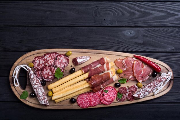 Conjunto de salsichas presunto salame jamon e azeitonas na placa de madeira