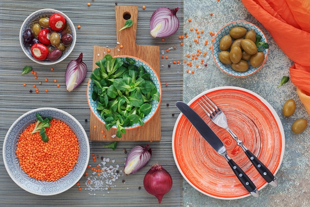 Conjunto de snacks mediterrânicos. azeitonas verdes e pretas, pão fresco multigrãos, salada de milho e cebola roxa sobre fundo de madeira velha. vista superior com espaço para texto