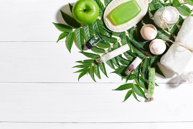 Conjunto de spa com toalha e sabonete em fundo branco de madeira com folhas verdes