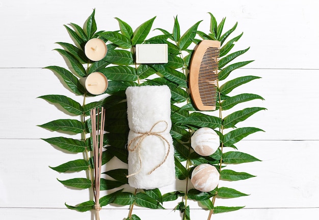 Conjunto de spa com toalha e sabonete em fundo branco de madeira com folhas verdes