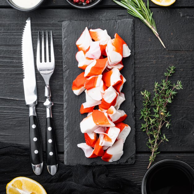 Conjunto de surimi de carne de caranguejo fresco com caranguejo azul, no fundo da mesa de madeira preta, vista superior plana