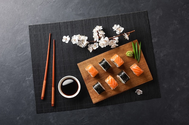 Conjunto de sushi e maki rolos com ramo de flores brancas na mesa de pedra. Vista do topo.