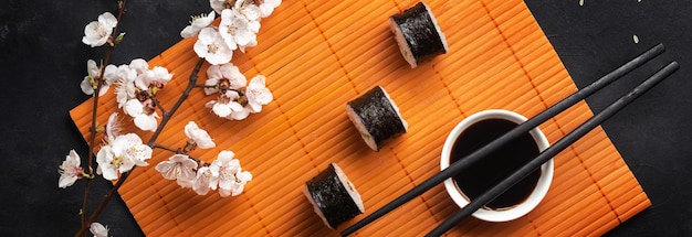 Conjunto de sushi e maki rolos com ramo de flores brancas na mesa de pedra. vista do topo.
