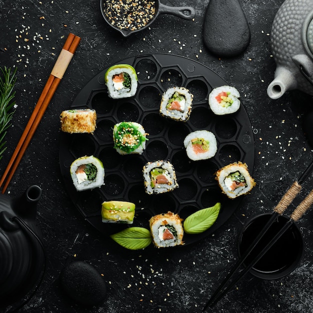 Conjunto de sushi saboroso e rolos de maki em fundo de pedra preta comida japonesa vista superior espaço livre para o seu texto