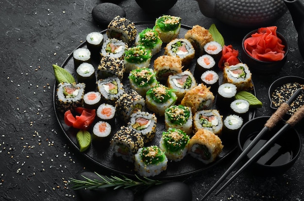 Conjunto de sushi tradicional em um prato preto. sushi e rolos em um fundo escuro.