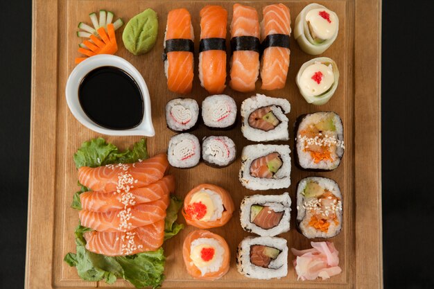 Conjunto de sushi variado servido na bandeja de madeira contra fundo preto