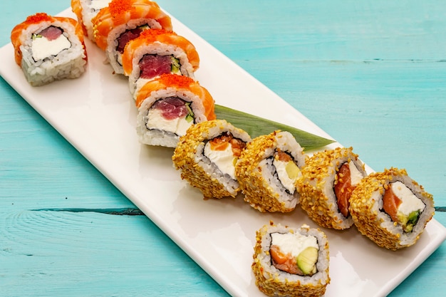 Foto conjunto de sushi variados. rolo japonês ou coreano com diferentes ingredientes frescos. na moda fundo turquesa