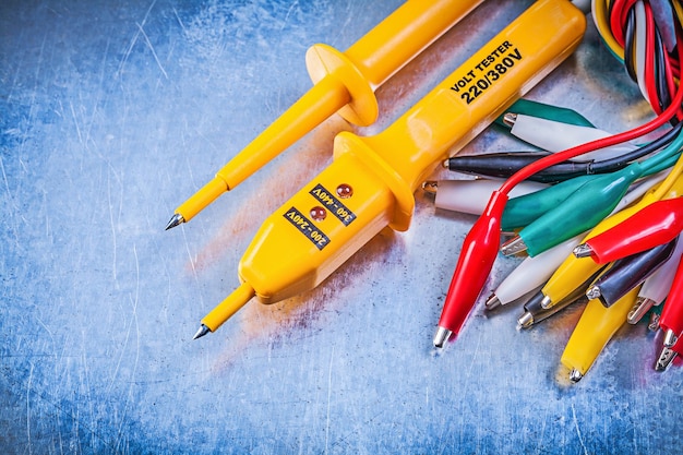 Conjunto de testador elétrico amarelo de cabos de clipe de crocodilo multicoloridos no conceito de eletricidade de fundo metálico