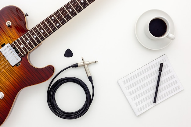 Conjunto de trabalho do músico com guitarra, nota e fones de ouvido