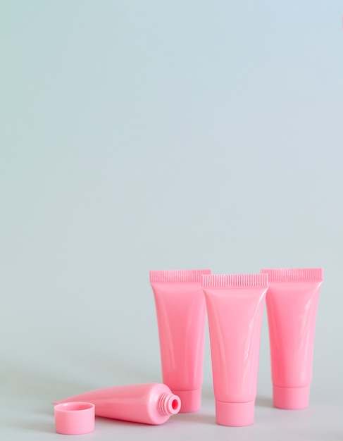 Conjunto de tubos cosméticos rosa em close-up de fundo cinza. Recipientes de produtos de spa para seu projeto. Copie o espaço