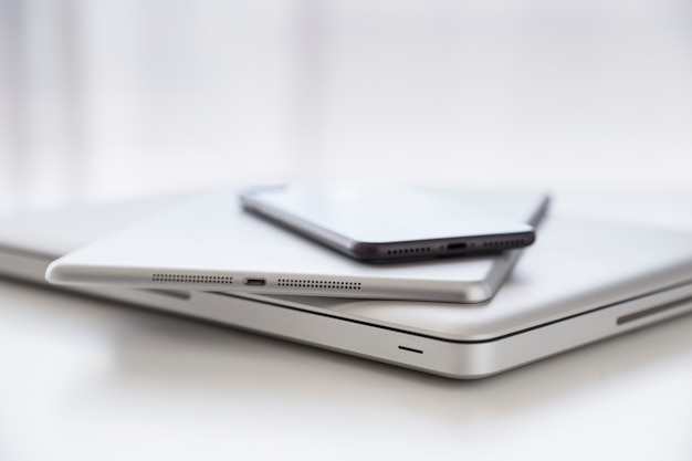 Conjunto de um computador, um tablet e um smatphone contra uma mesa branca