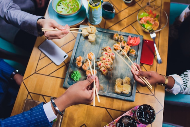 Conjunto de um jantar em família segurando os pauzinhos no sushi. Vista plana leiga, superior.