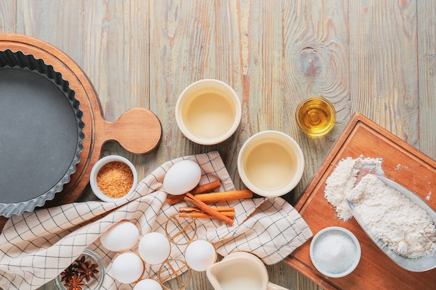 Conjunto de utensílios de cozinha e ingredientes para preparar a padaria em fundo de madeira