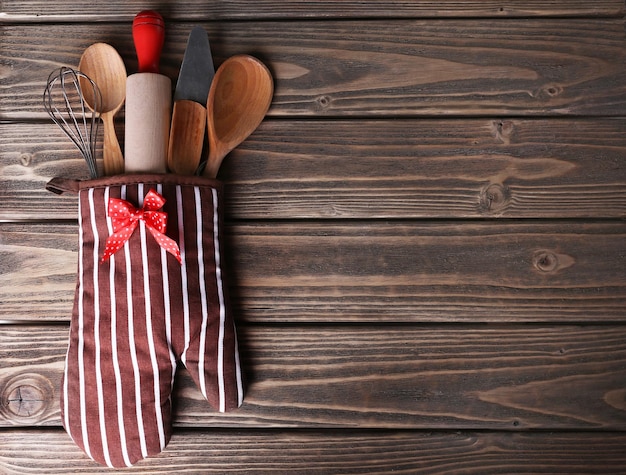 Conjunto de utensílios de cozinha em luva em fundo de pranchas de madeira