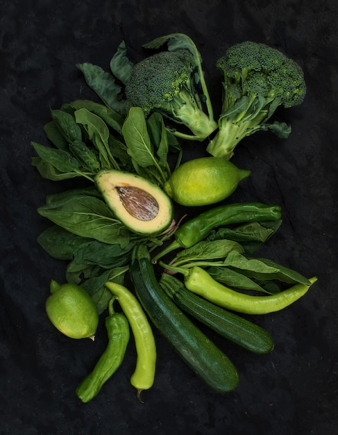 Conjunto de vegetais verdes crus. Brócolis, abacate, pimenta, espinafre, abobrinha, limão na mesa de pedra escura