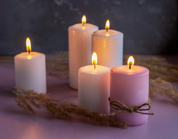 Conjunto de velas de cera branca e rosa com flores secas em luzes baixas