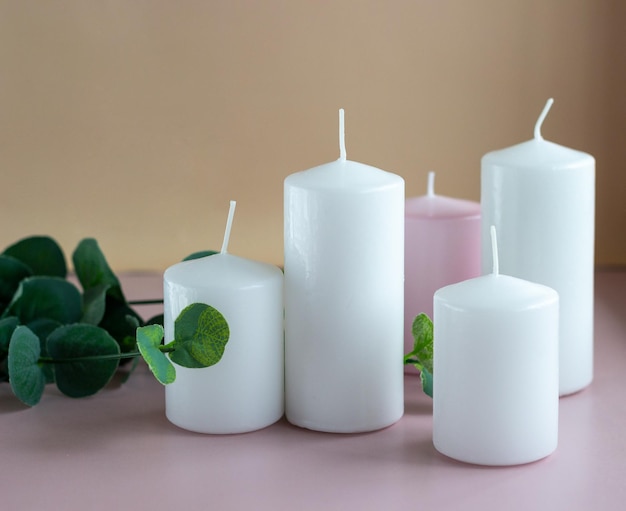 Conjunto de velas de cera branca e rosa com folhas verdes