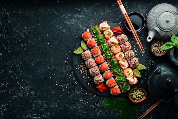 Conjunto de vista superior de rolos de sushi em uma placa de pedra preta Comida japonesa tradicional em um fundo de pedra preta