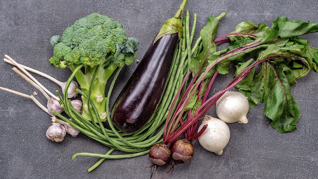 Conjunto de vitaminas vegetais de berinjela, abobrinha, feijão verde e brócolis na mesa cinza