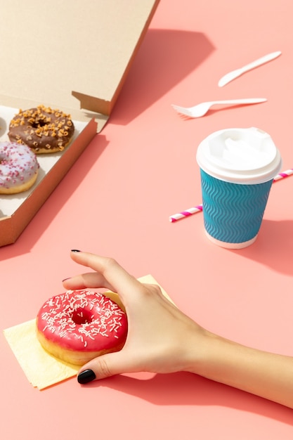 Conjunto de deliciosos donuts coloridos en caja de papel sobre superficie rosa