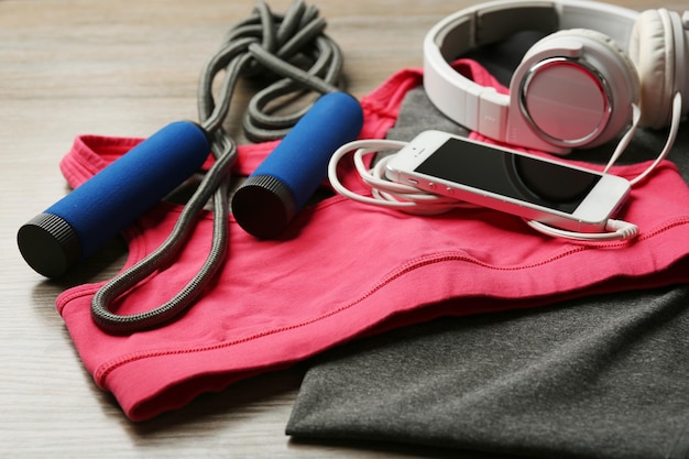 Conjunto para deportes y teléfonos inteligentes con auriculares en el fondo de la mesa de madera