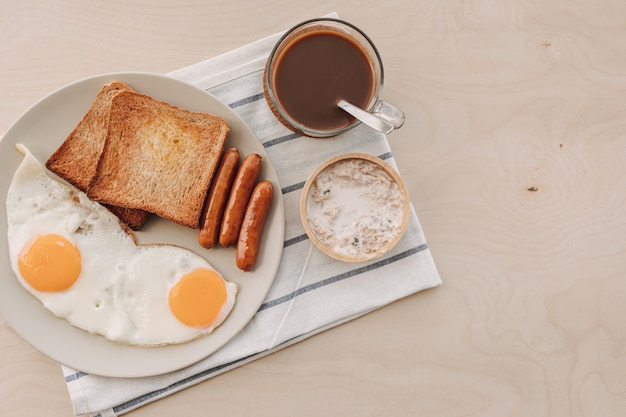 Conjunto de desayuno de huevos fritos, salchichas de pan tostado y atún para untar