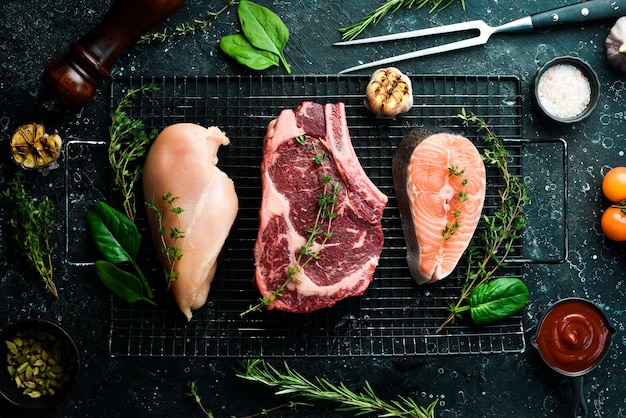 Un conjunto de diferentes carnes filete de salmón filete de ternera y pechuga de pollo sobre un fondo de piedra negra