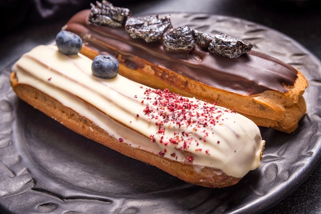 Conjunto de diferentes pasteles de eclair sobre fondos oscuros