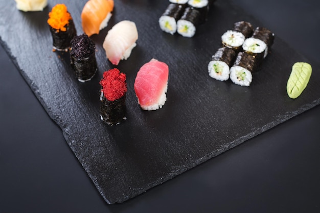 Un conjunto de diferentes rollos de sushi con caviar sobre fondo negro