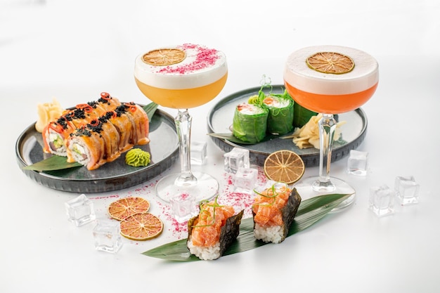 Conjunto de diferentes rollos de sushi y cócteles sobre fondo blanco.