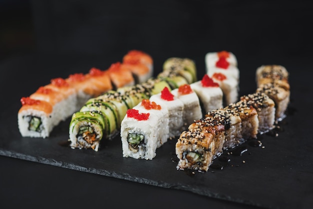 Conjunto de diferentes rollos de sushi sobre fondo negro