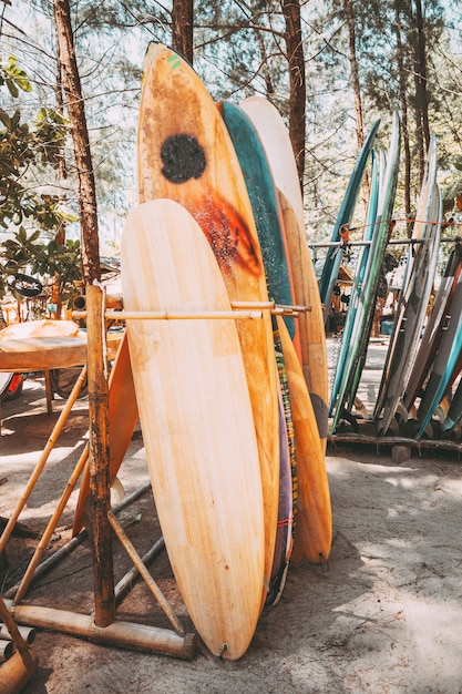 Conjunto de diferentes tablas de surf de colores en una pila disponible para alquilar en la playa. Tablas de surf verticales, efecto de tono de color vintage.