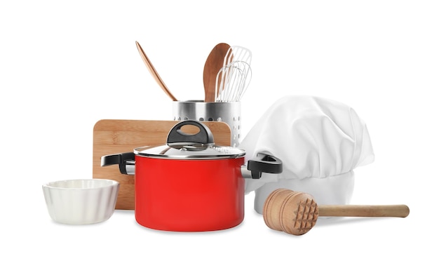 Conjunto de diferentes utensilios de cocina y gorro de chef sobre fondo blanco.