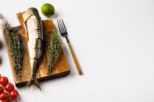 Conjunto entero de pescado caballa ahumado, sobre fondo de mesa de piedra blanca, con espacio para copiar texto