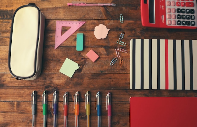 Foto conjunto escolar con calculadora de cuadernos y estuche de lápices sobre fondo de madera