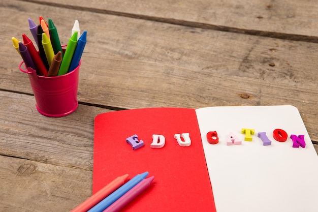 Conjunto escolar con inscripción de bloc de notas de educación y crayones en mesa de madera marrón