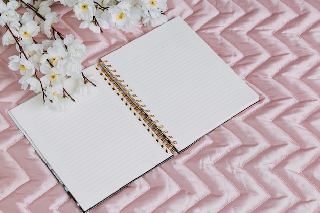 Foto conjunto de escritorio de accesorios para mujer - cuaderno con bolígrafo, flor en blanco rosa.