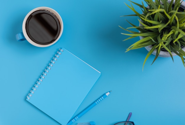 Conjunto de espacio de trabajo azul de notas, bolígrafo, anteojos y taza de café, vista superior