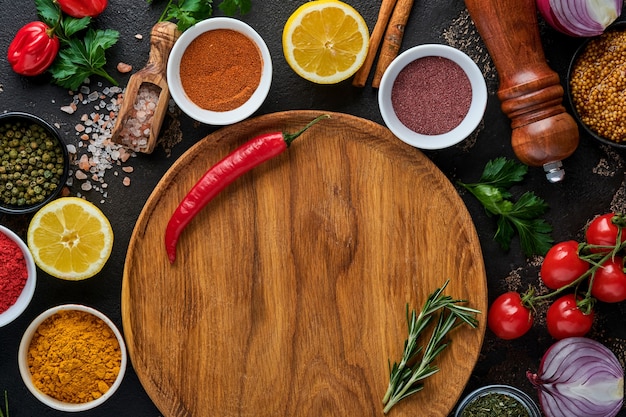 Conjunto de especias y hierbas aromáticas indias sobre un fondo de piedra negra. Cúrcuma, eneldo, pimentón, canela, azafrán, albahaca y romero en una cuchara. Vista superior. Bosquejo.