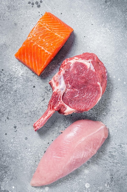 Conjunto de filetes de carne cruda, salmón, ternera y pavo en una mesa de cocina Fondo gris Vista superior