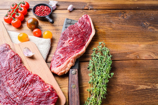 Conjunto de filetes de picanha sobre viejo cuchillo de carnicero americano con condimentos en la mesa de madera. Vista lateral, espacio para texto.