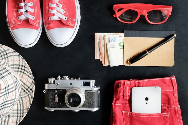 Conjunto de fotografía de cine de arte fino vintage de zapatillas rojas, gafas rojas, jeans rojos, cámara vintage, teléfono blanco, cuaderno y dinero, lápiz óptico, sombrero a cuadros