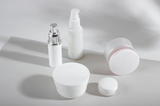 Conjunto de frascos y frascos de cosméticos blancos con sombras duras.